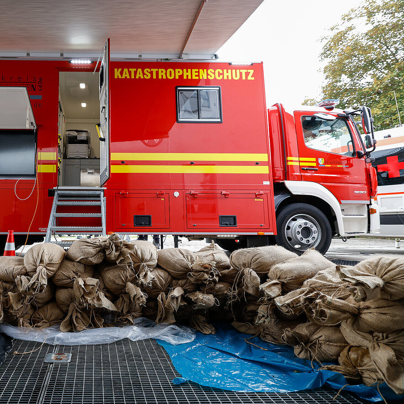 Ein Feuerwehrauto seitlich unter einer Brücke, vor dem Auto liegen viele Sandsäcke
