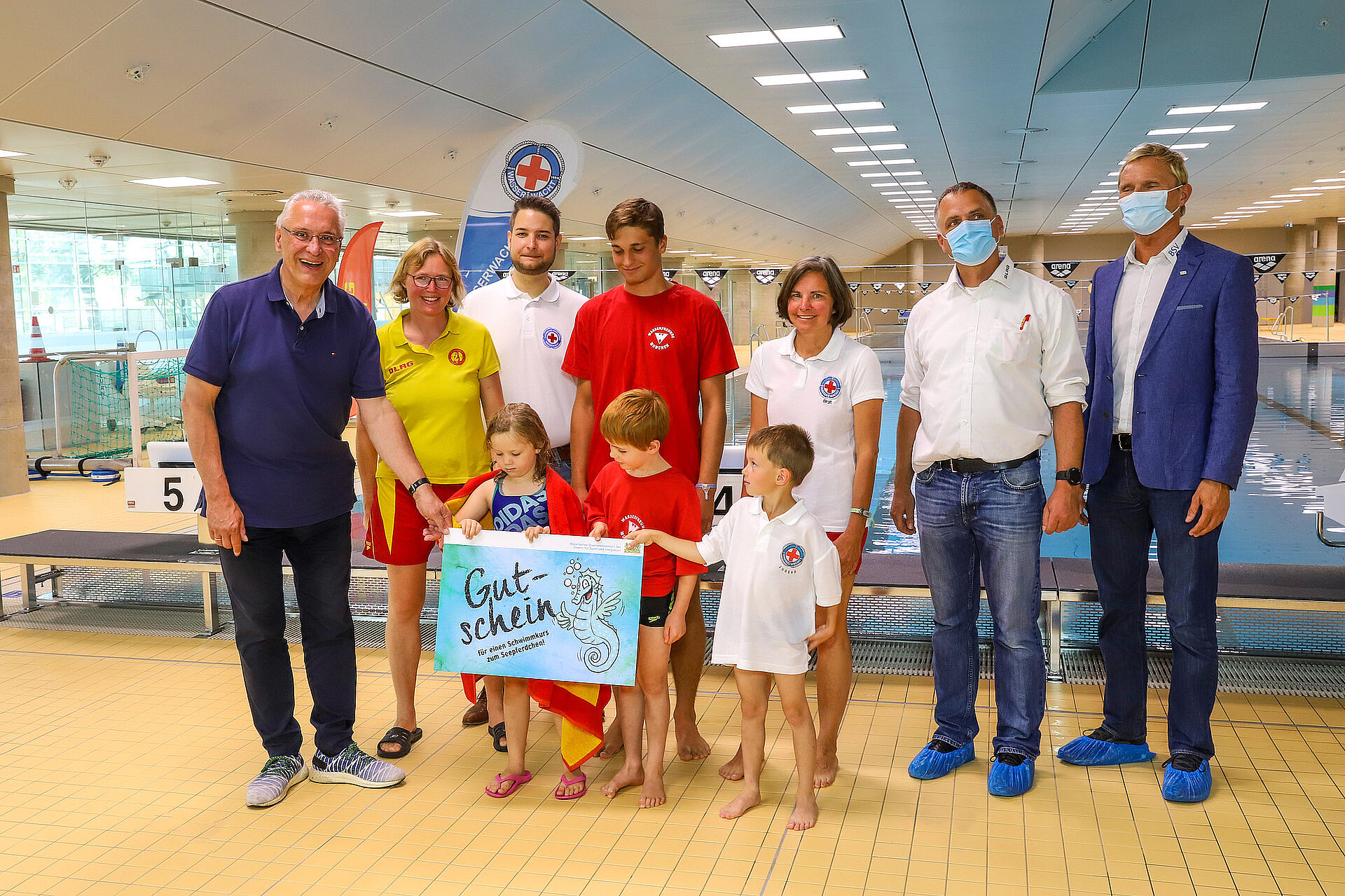Sportminister Herrmann mit Vertretern des DLRG, der Wasserwacht und des Bayerischen Schwimmverbands mit Kindern und Seepferdchen-Gutschein 