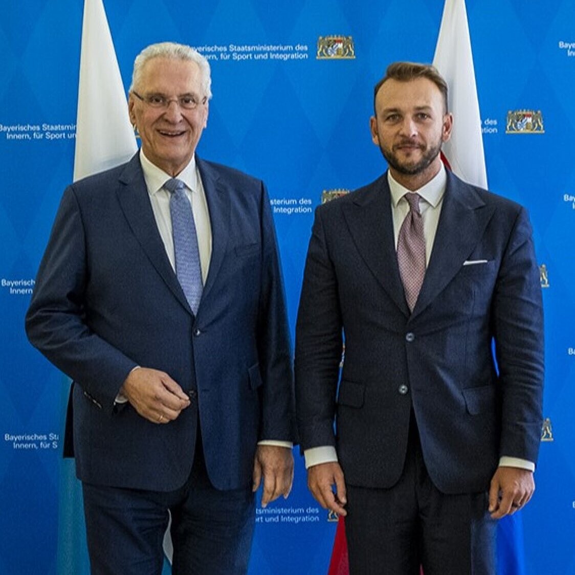 Auf dem Bild sind Innenminister Joachim Herrmann und sein slowakischer Amtskollege Matúš Šutaj Eštok vor den Fahnen der Länder Bayern und der Slowakei zu sehen.