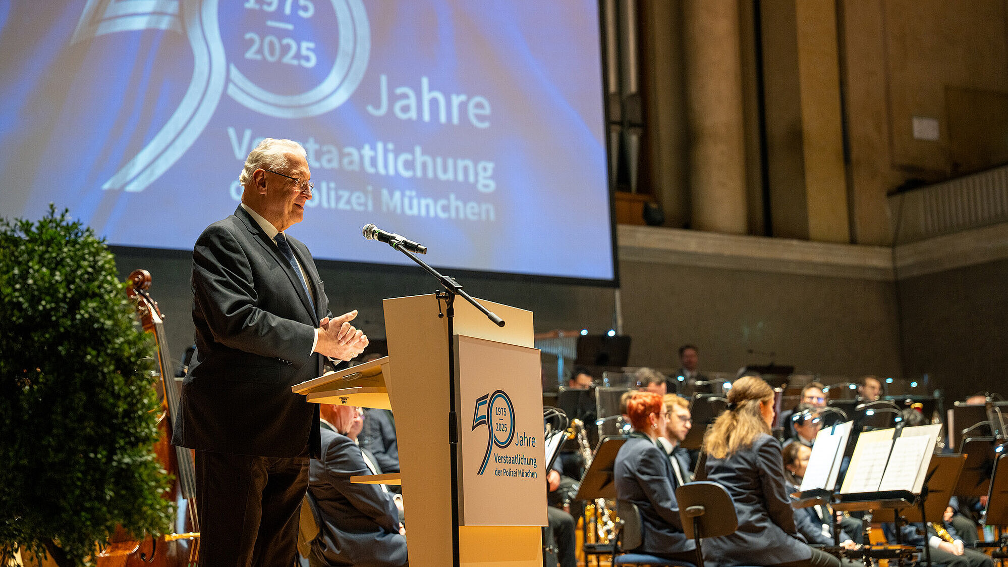 Innenminister Joachim Herrmann am Rednerpult im Hintergrund ein Bildschirm mit der Aufschrift 50 Jahre Polizei Verstaatlichung