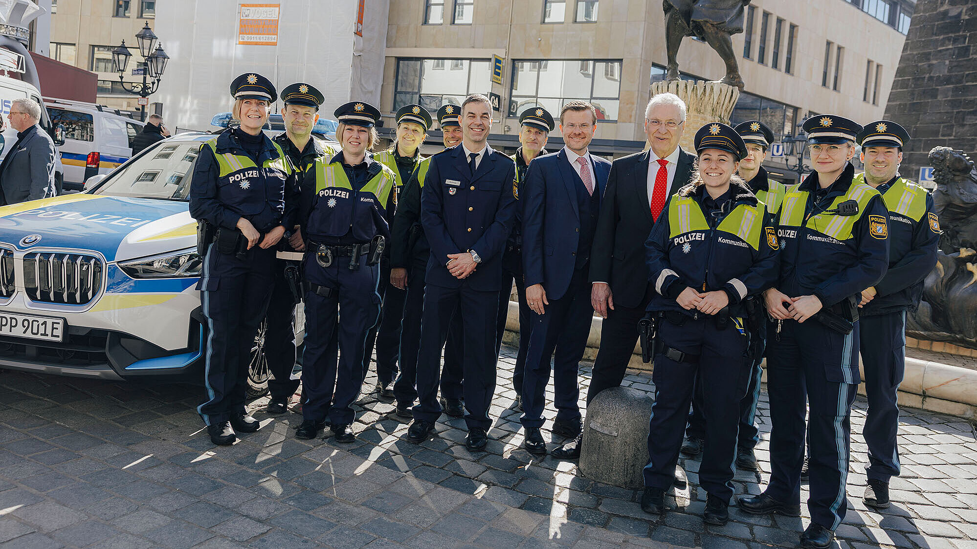 Eine Gruppe von Polizeibeamten steht neben einem Einsatzfahrzeug.