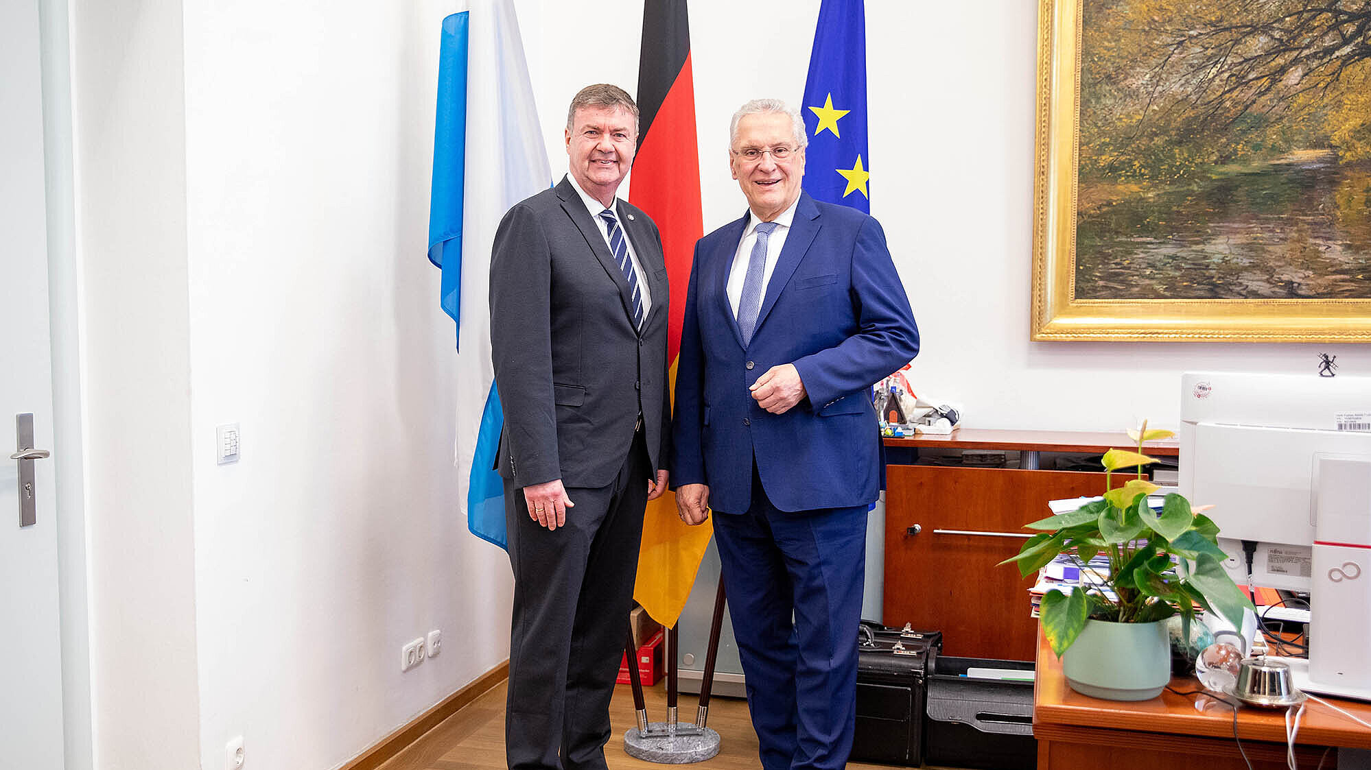 Innenminister Joachim Herrmann und Harald Pickert, BLKA-Präsident a.D., im Ministerbüro vor einem Fahnenset