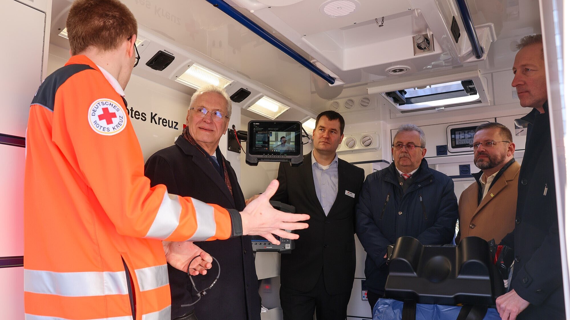 Mann vom Rettungsdienst erklärt Innenminister Joachim Herrmann in Rettungswagen das Telenotarztsystem.