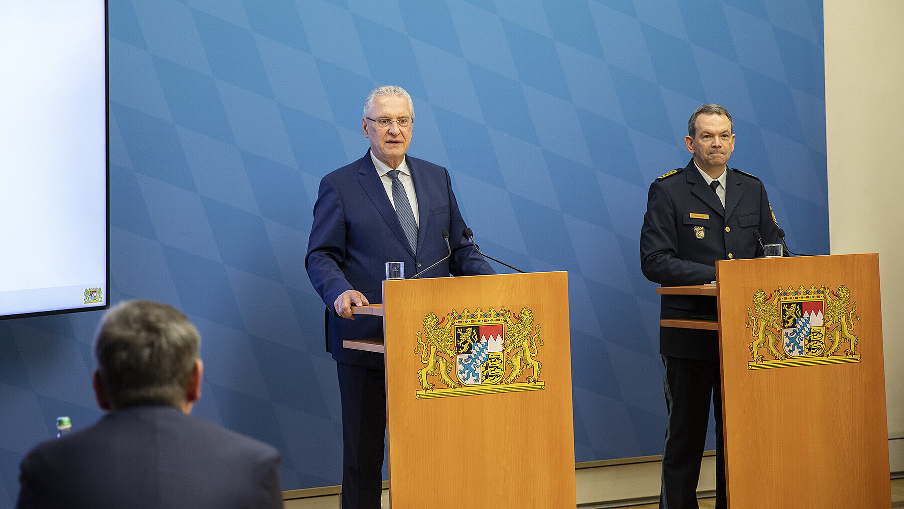 Herrmann und Schwald bei Präsentation hinter Rednerpulten