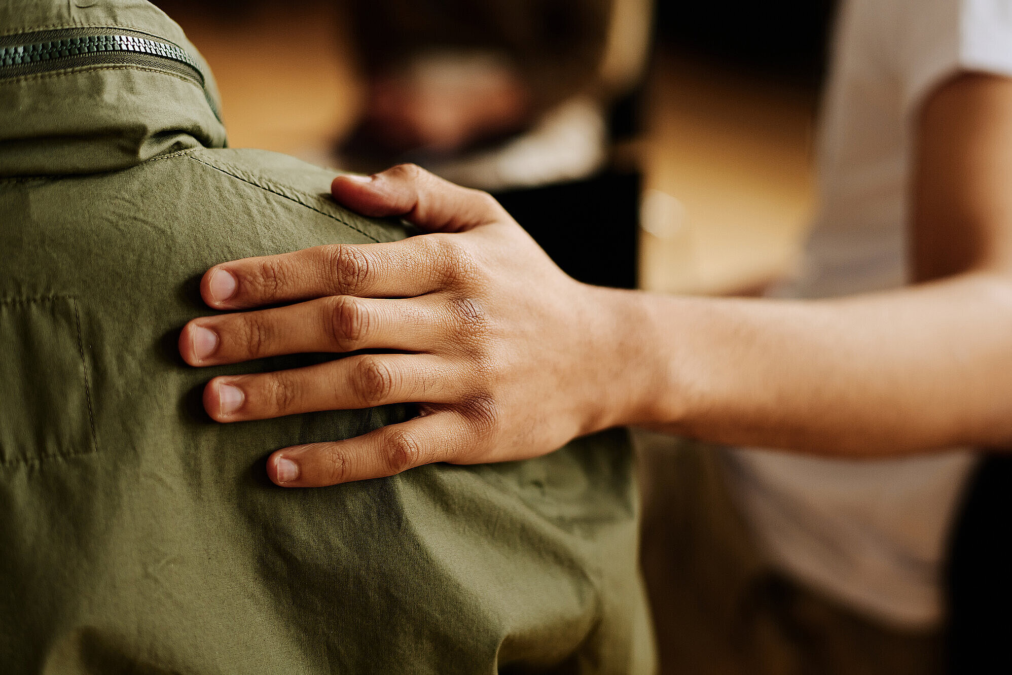 Eine Hand die sich auf eine Schulter legt
