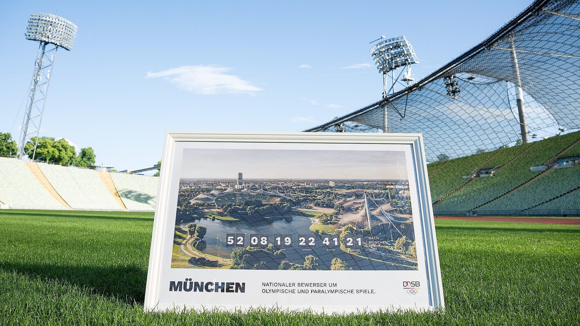 Bild im Rahmen mit Olympiastadion München "Nationaler Bewerber um Olympische und Paralympische Spiele" auf dem Rasen im Olympiastadion München