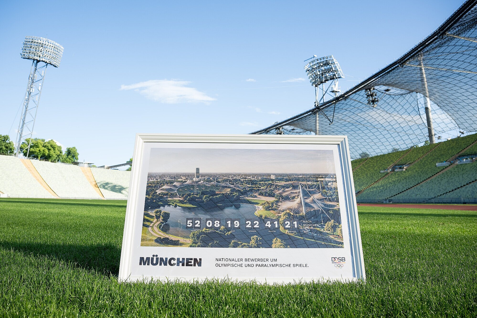 Bild im Rahmen mit Olympiastadion München "Nationaler Bewerber um Olympische und Paralympische Spiele" auf dem Rasen im Olympiastadion München