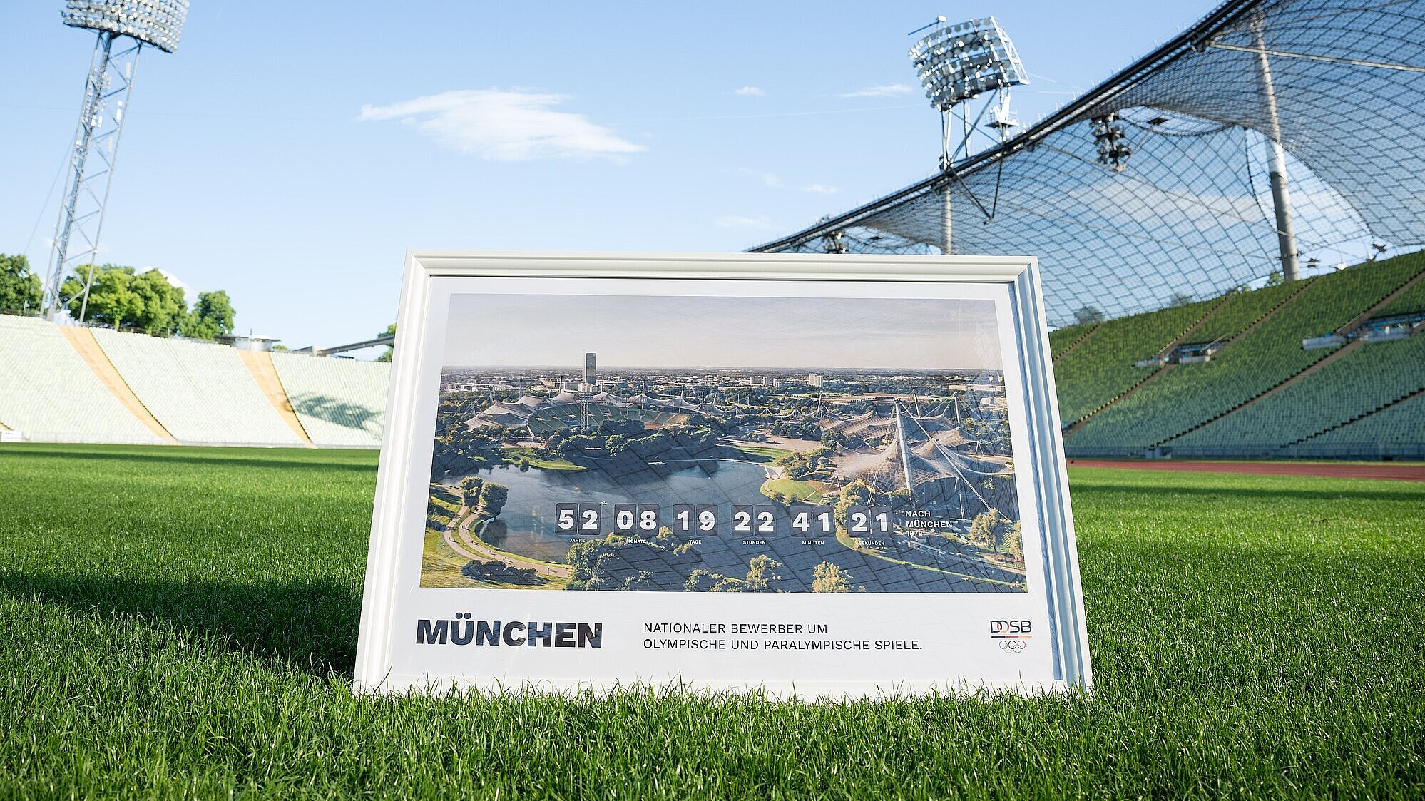 Bild im Rahmen mit Olympiastadion München "Nationaler Bewerber um Olympische und Paralympische Spiele" auf dem Rasen im Olympiastadion München