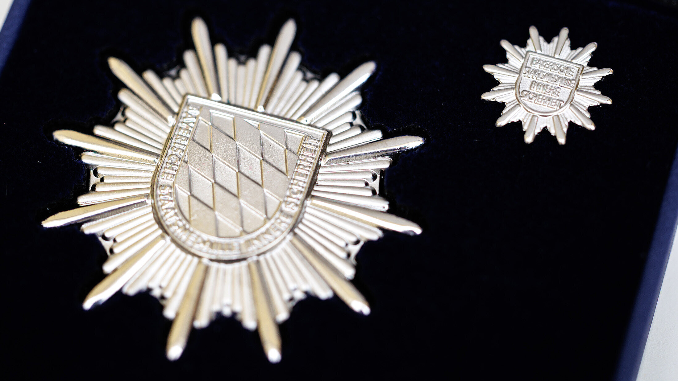 Silberner Stern der Sicherheit in groß und klein auf einem schwarzen Samtkissen