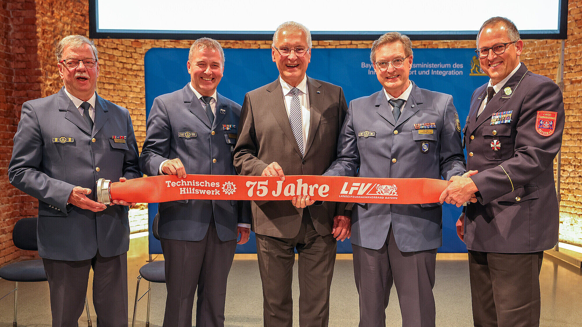 Gruppenbild mit Herrmann und vier weiteren Personen, die ein Banner halten mit 75 Jahre THW