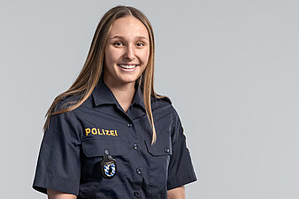 Magdalena Matschina vor hellem Hintergrund, trägt dunkles Polizeihemd mit Aufschrift Polizei gestickt.