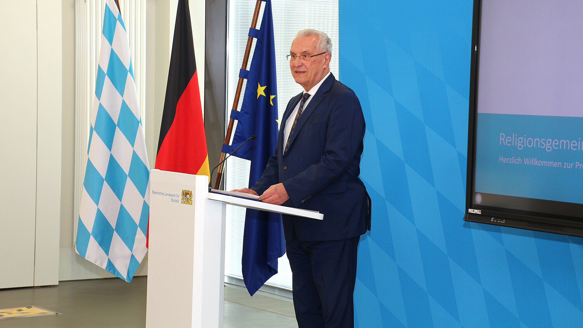 auf dem Bild: Innenminister Joachim Herrmann am Rednerpult bei der Pressekonferenz im Bayerischen Landesamt für Statistik in Fürth
