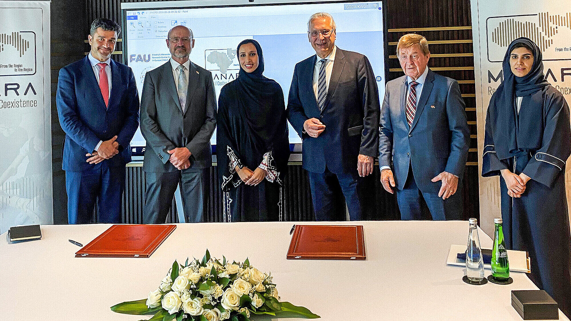 Gruppenfoto vor Tisch mit Ledermappen und Blumen