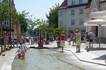 Viele Personen auf dem Marktplatz in Rosenheim und um ein Wasserbecken herum
