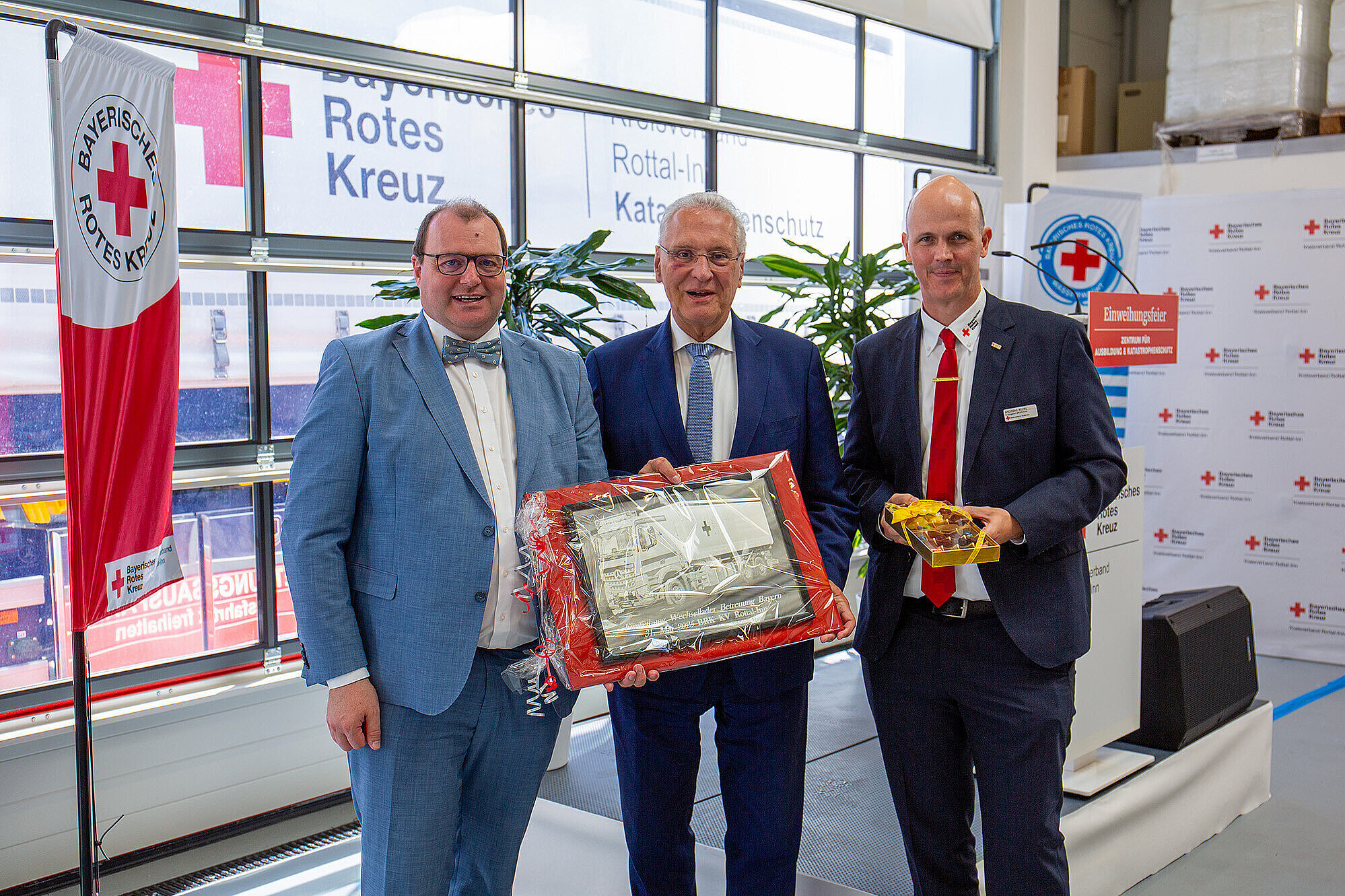 Gruppenbild Innenminister Herrmann mit Vertretern des BRK Kreisverband Rottal, Herrmann hält eine Torte in der Hand, auf der ein LkW abgebildet ist