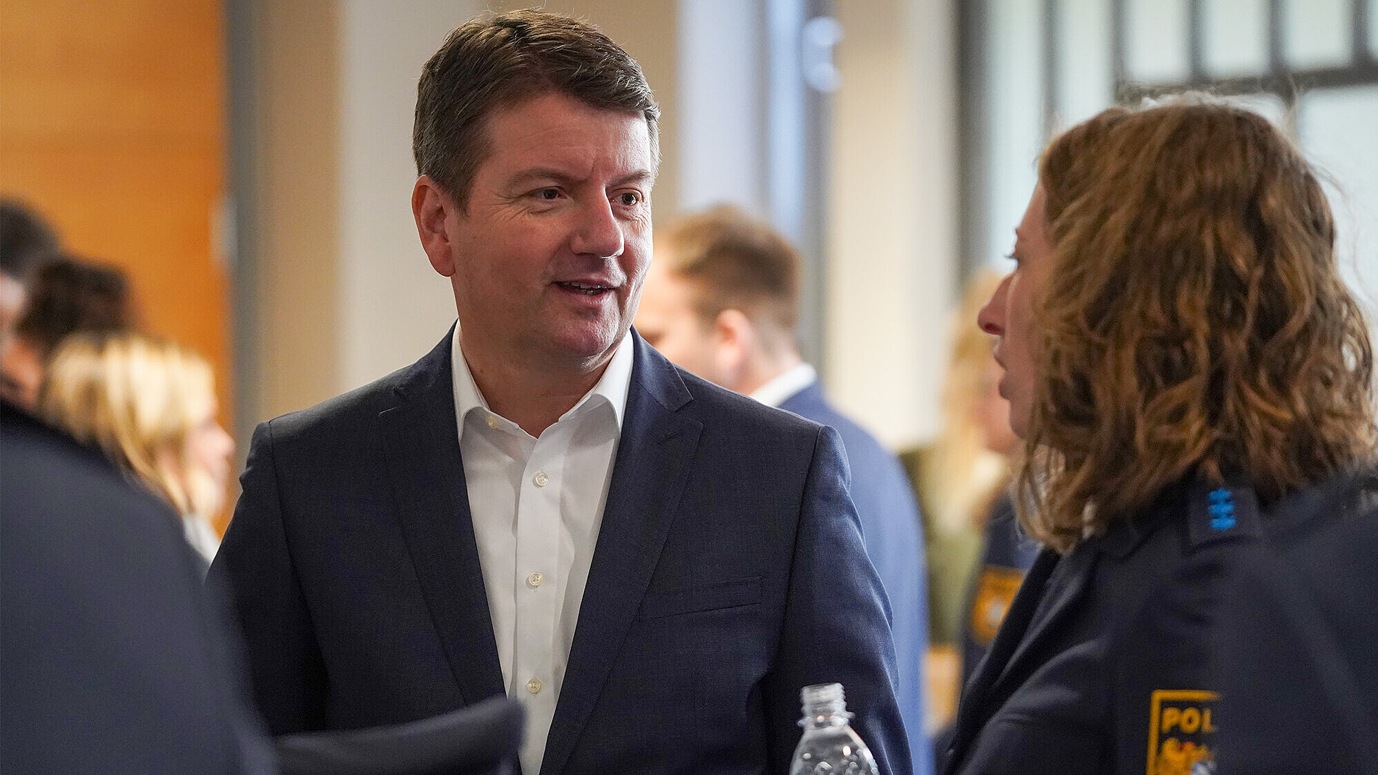 Ein Mann im Anzug im Gespräch mit einer Frau in Uniform.