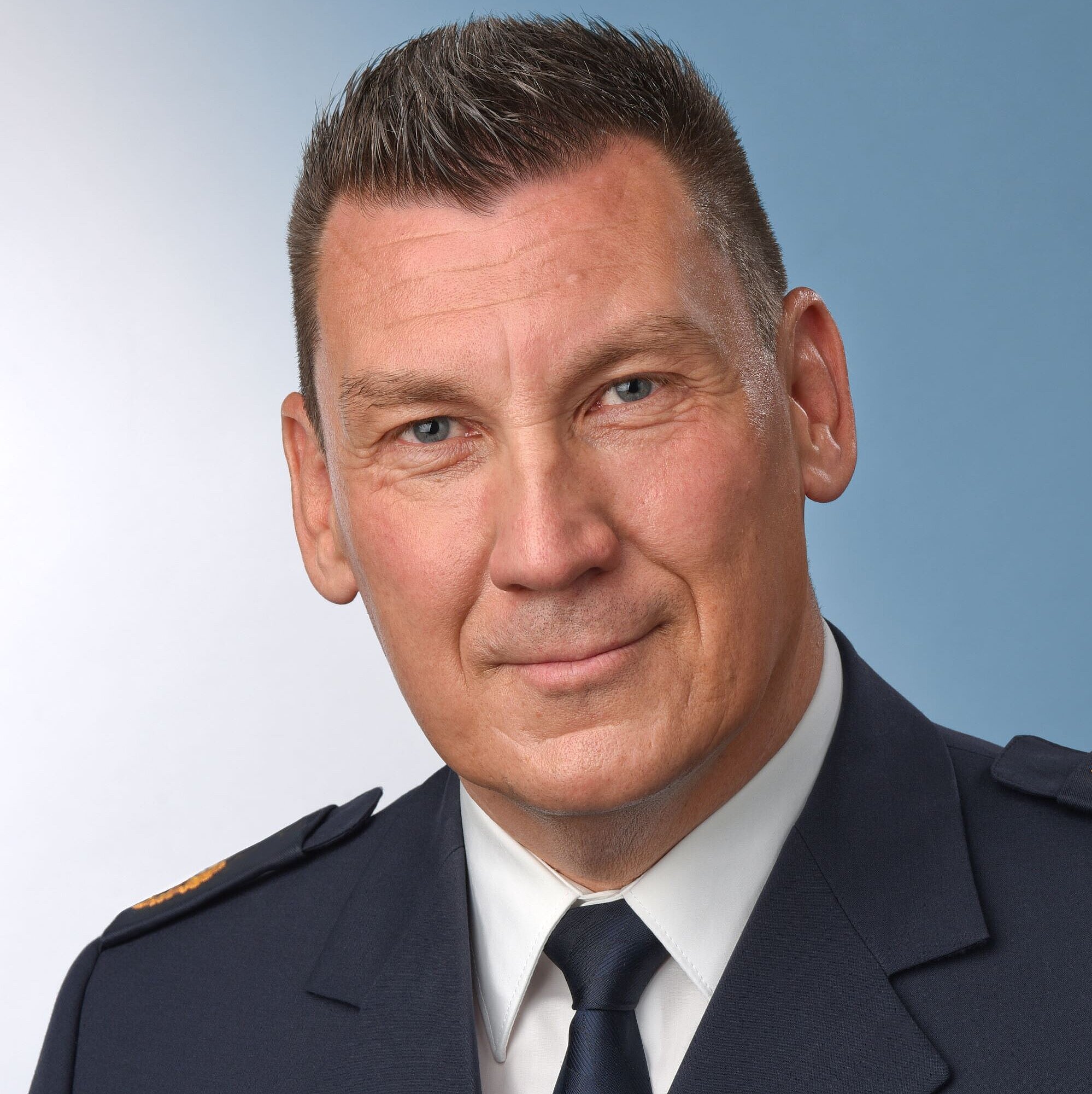 Auf dem Bild ist der neue Polizeipräsident Stefan Weis in Dienstuniform zu sehen, der Hintergrund ist blau-weiß