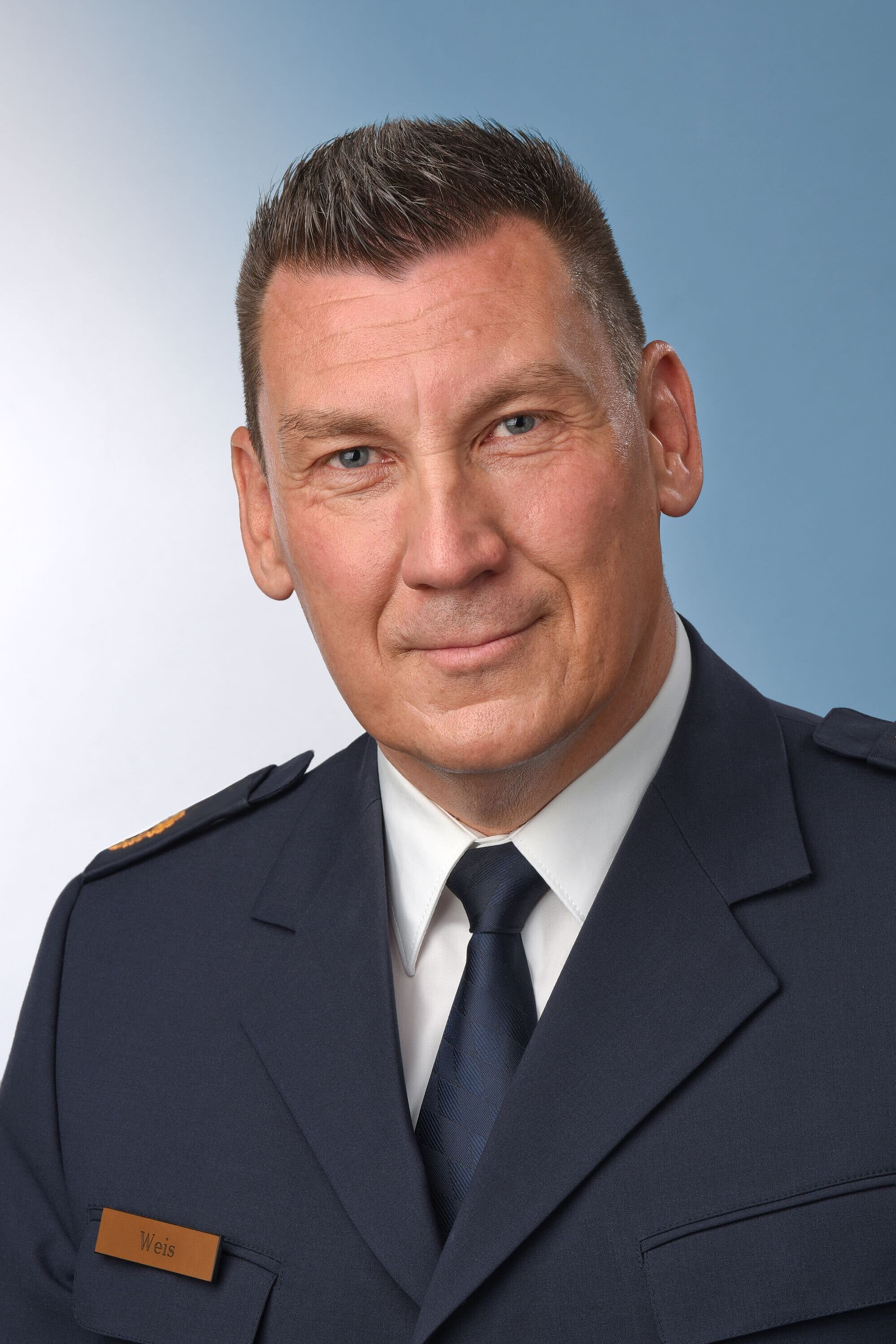 Auf dem Bild ist der neue Polizeipräsident Stefan Weis in Dienstuniform zu sehen, der Hintergrund ist blau-weiß