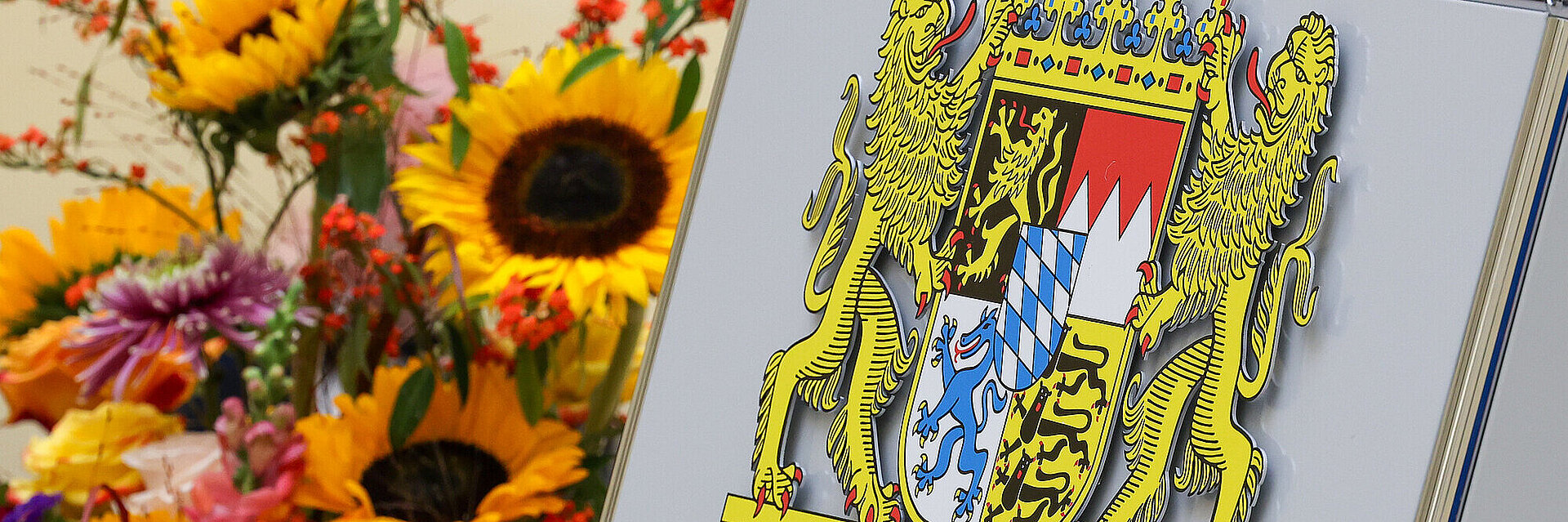 Rednerpult mit Staatswappen und im Hintergrund ein bunter Blumenstrauß