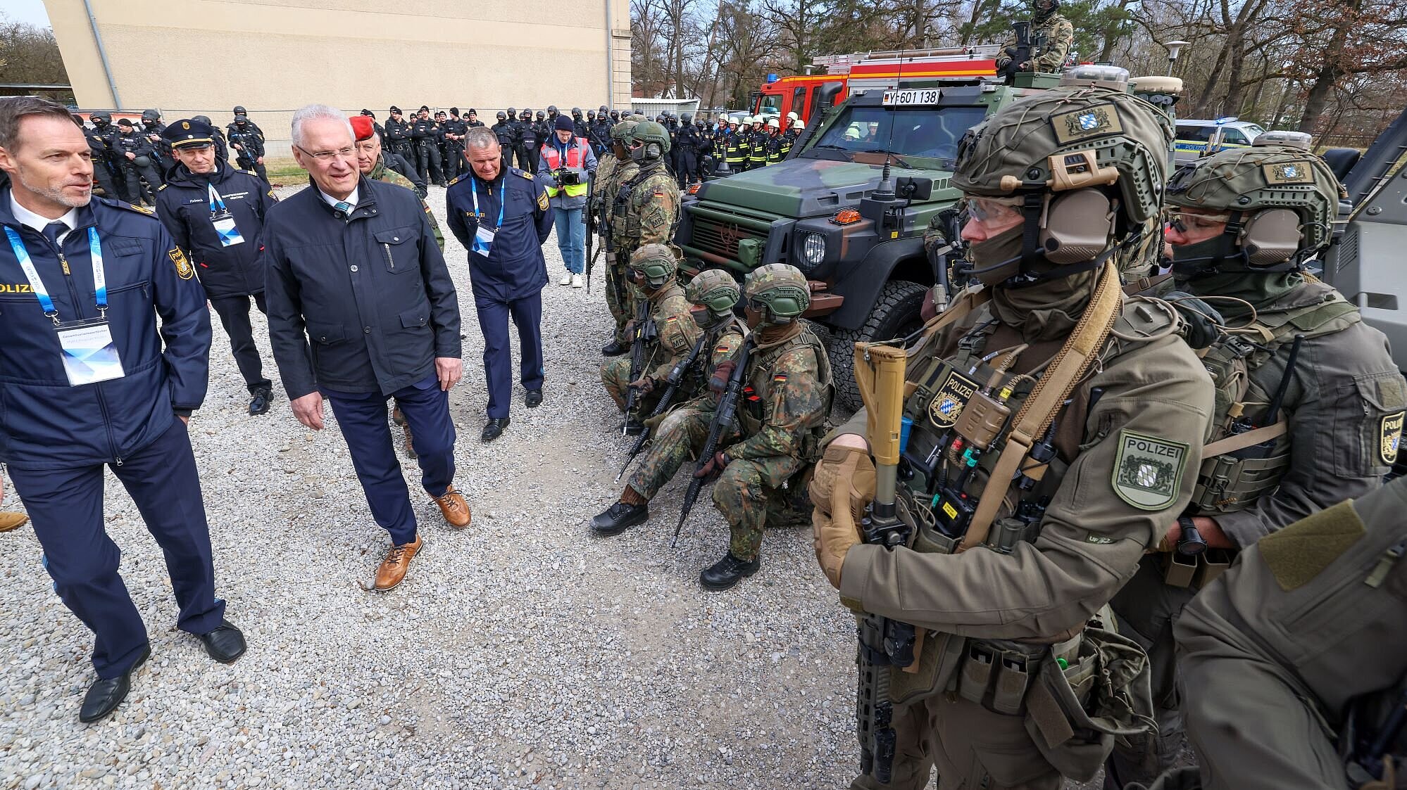 Auf dem Bild sind viele Soldaten und Polizisten in Uniform zu sehen, Innenminister Herrmann schreitet an ihnen vorbei.