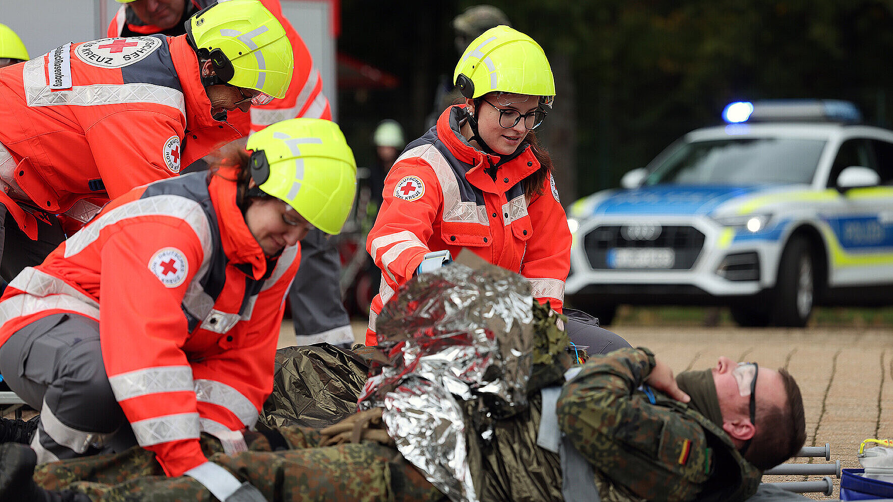 Auf dem Bild sind Sanitäter vom Bayerischen Roten Kreuz zu sehen, wie sie einen Bundeswehr-Soldaten bei der Terrorabwehrübung RoadTEX verarzten.