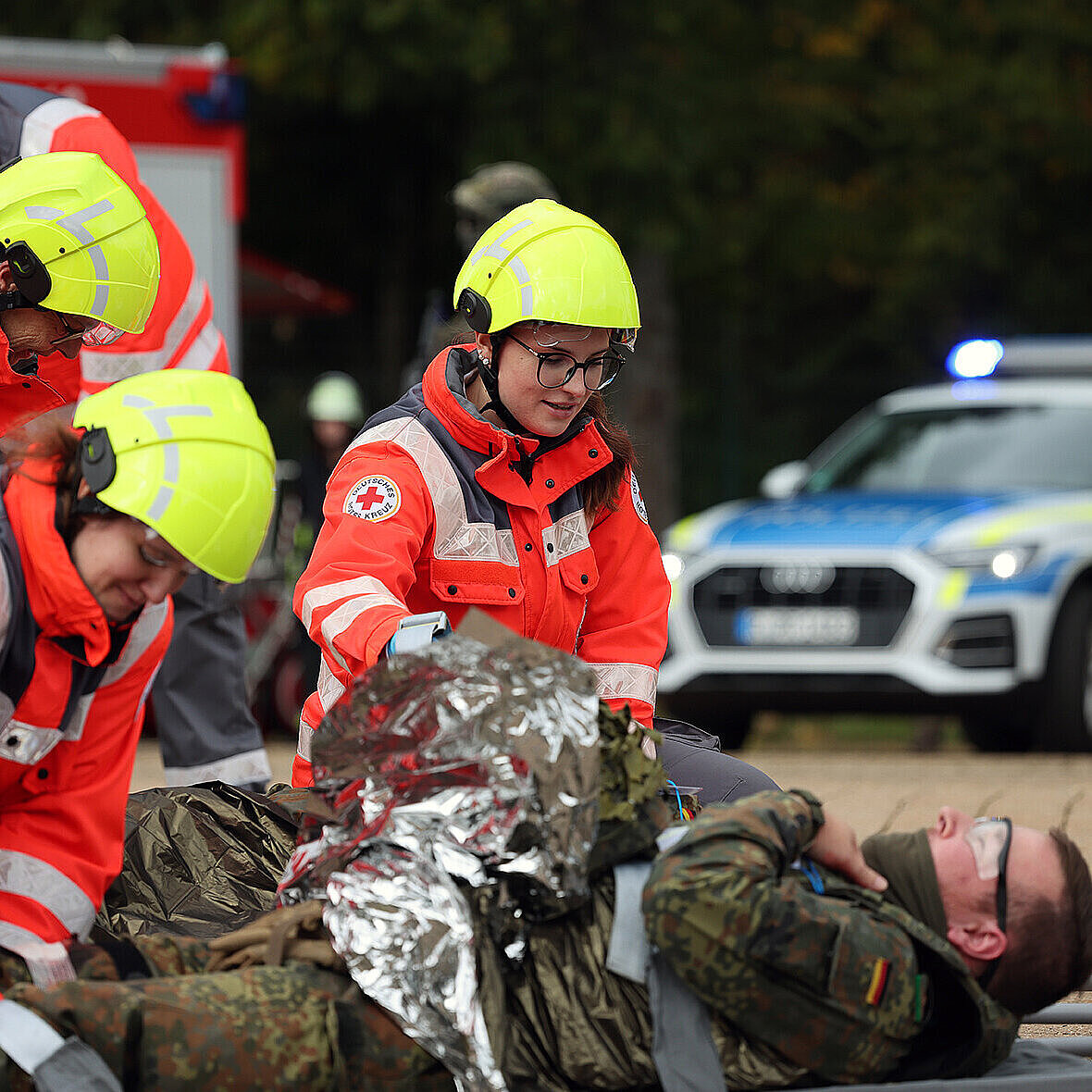 Auf dem Bild sind Sanitäter vom Bayerischen Roten Kreuz zu sehen, wie sie einen Bundeswehr-Soldaten bei der Terrorabwehrübung RoadTEX verarzten.