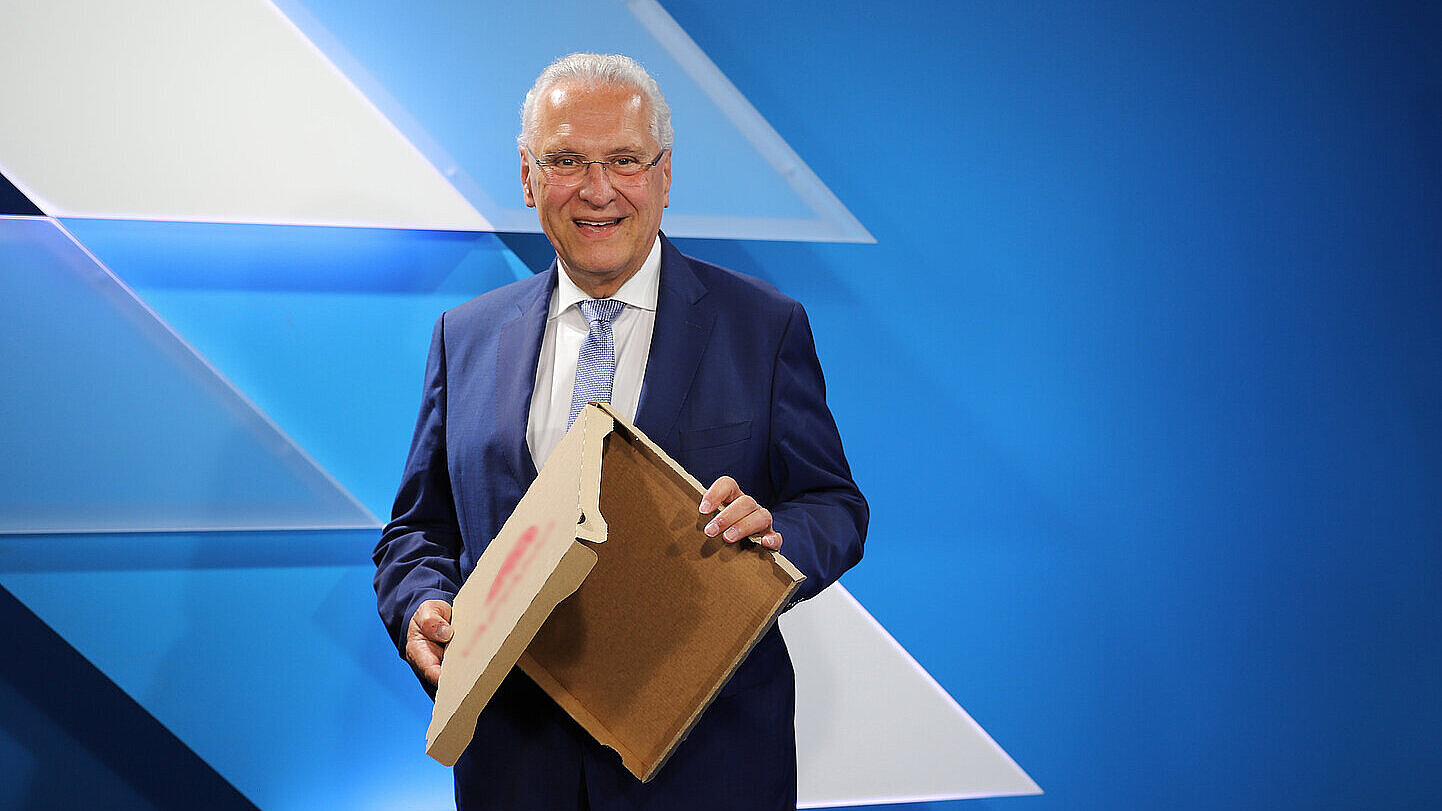 Innenminister Joachim Herrmann hält einen leeren Pizzakarton