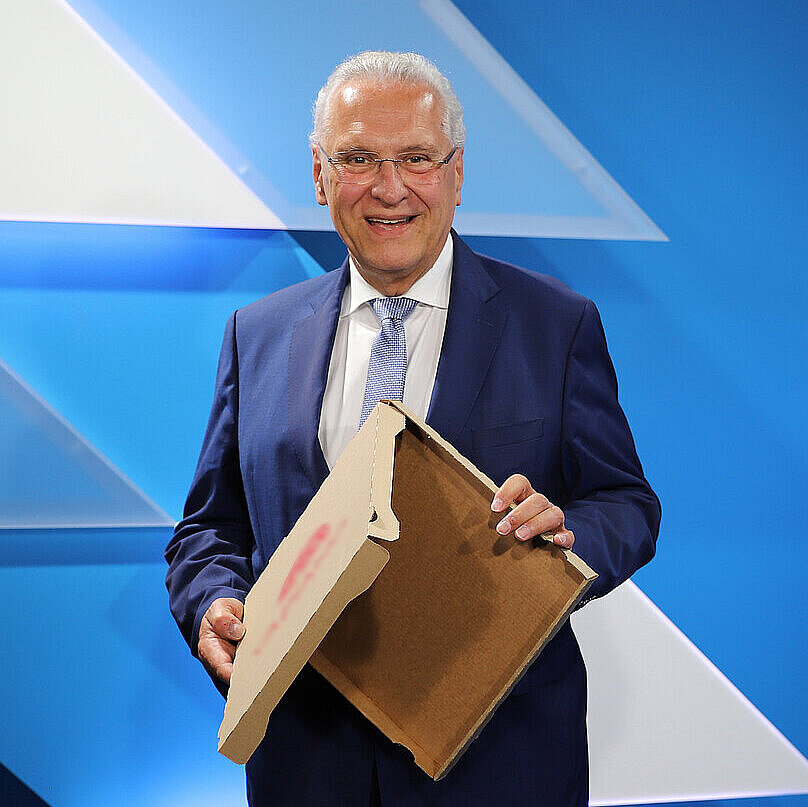 Innenminister Joachim Herrmann hält einen leeren Pizzakarton