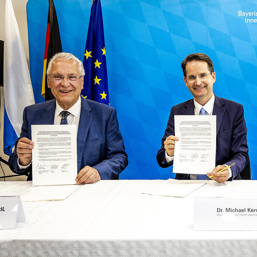 Herrmann, Kern und Gürtner am Tisch, halten drei unterzeichnete Papiere hoch, dahinter Pressewand