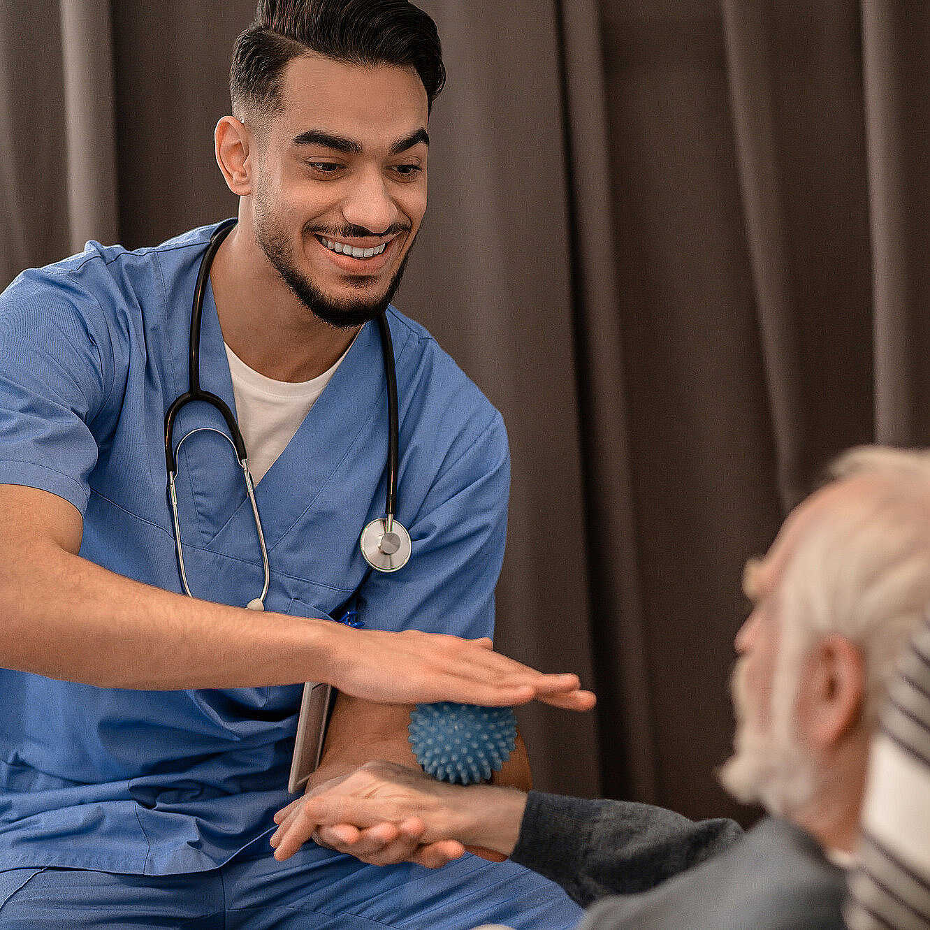 Lächelnder, freundlicher Physiotherapeut führt eine Physiotherapie-Sitzung zu Hause durch.