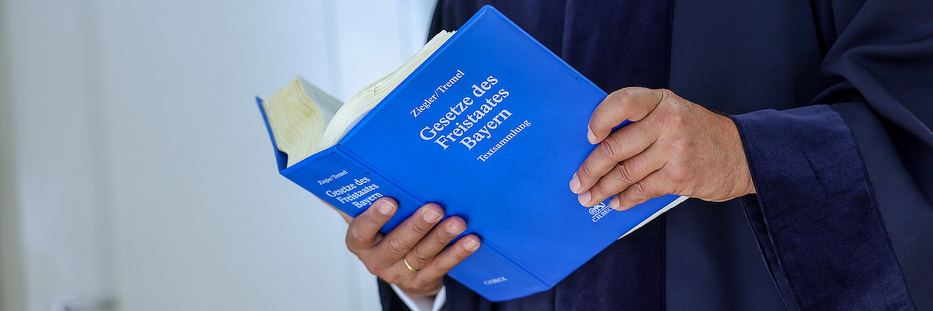 Richter in seiner Robe mit aufgeschlagenem Gesetzbuch in der Hand