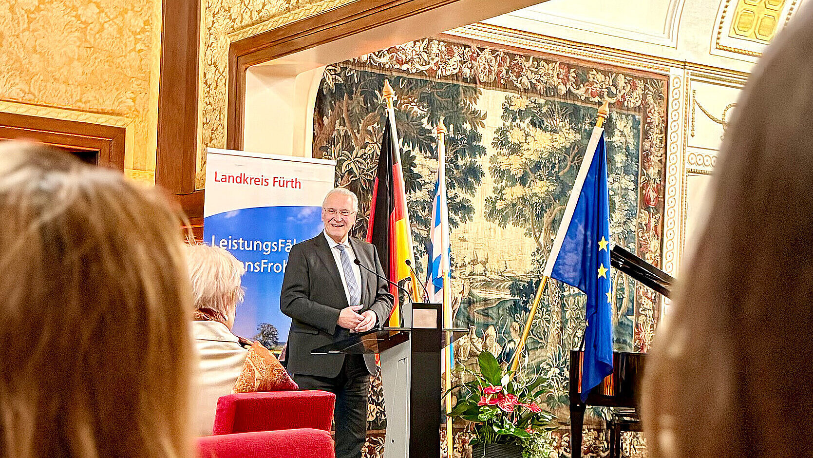Innenminister Herrmann bei der Einbürgerungsfeier im Rathaus an einem Rednerpult stehend mit Blick ins Publikum.