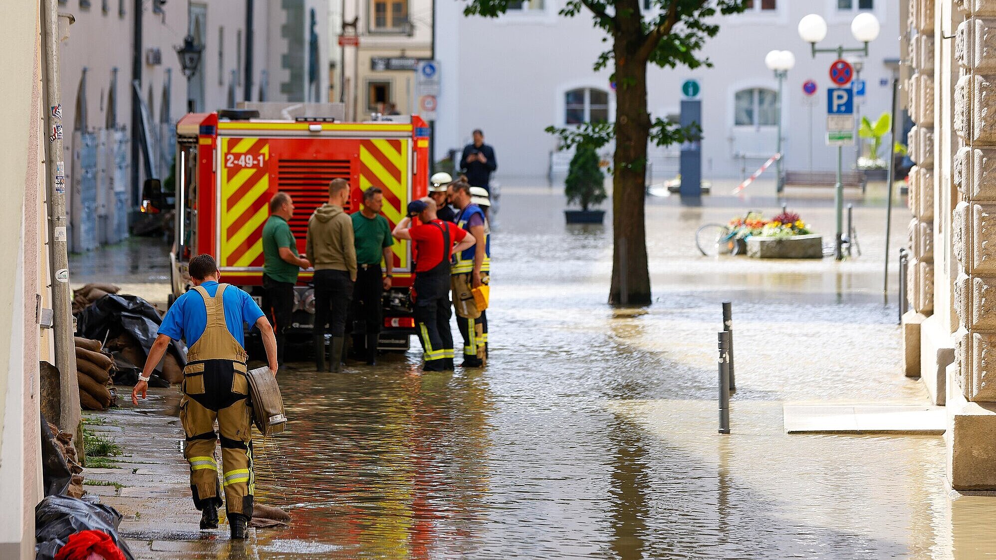 Einsatzkräfte in einer von Hochwasser überfluteten Straße mit Einsatzfahrzeug