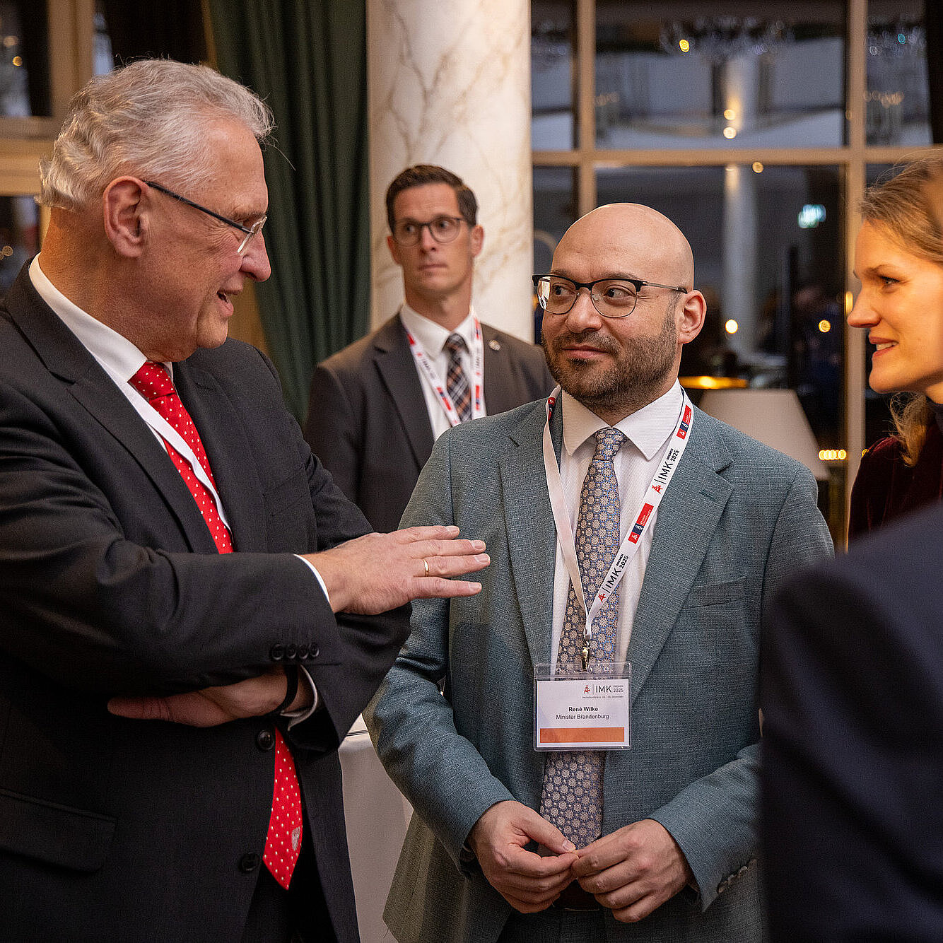 Innenminister Joachim Herrmann im Gespräch mit René Wilke, dem Minister von Brandenburg, daneben weitere Personen, die zuhören