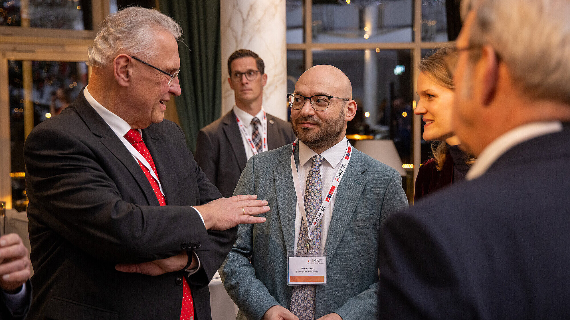 Innenminister Joachim Herrmann im Gespräch mit René Wilke, dem Minister von Brandenburg, daneben weitere Personen, die zuhören