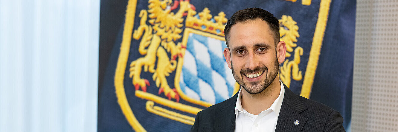 Jurist mit Laptop und Gesetzesbänden vor Polizei-Rollup