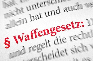 Paragraph Waffengesetz in roter Schrift in einem Wörterbuch, außen herum verschwommener Text