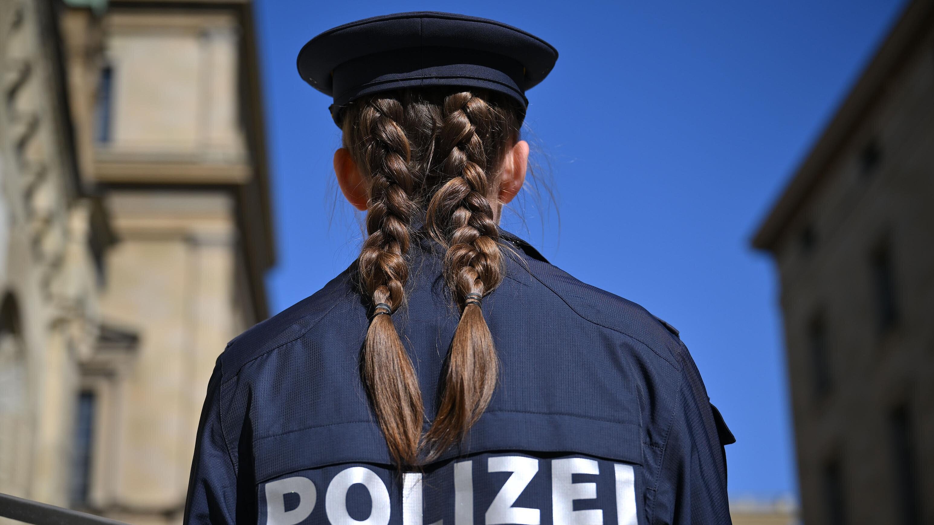 Polizistin von hinten, im  Hintergrund Gebäude in München