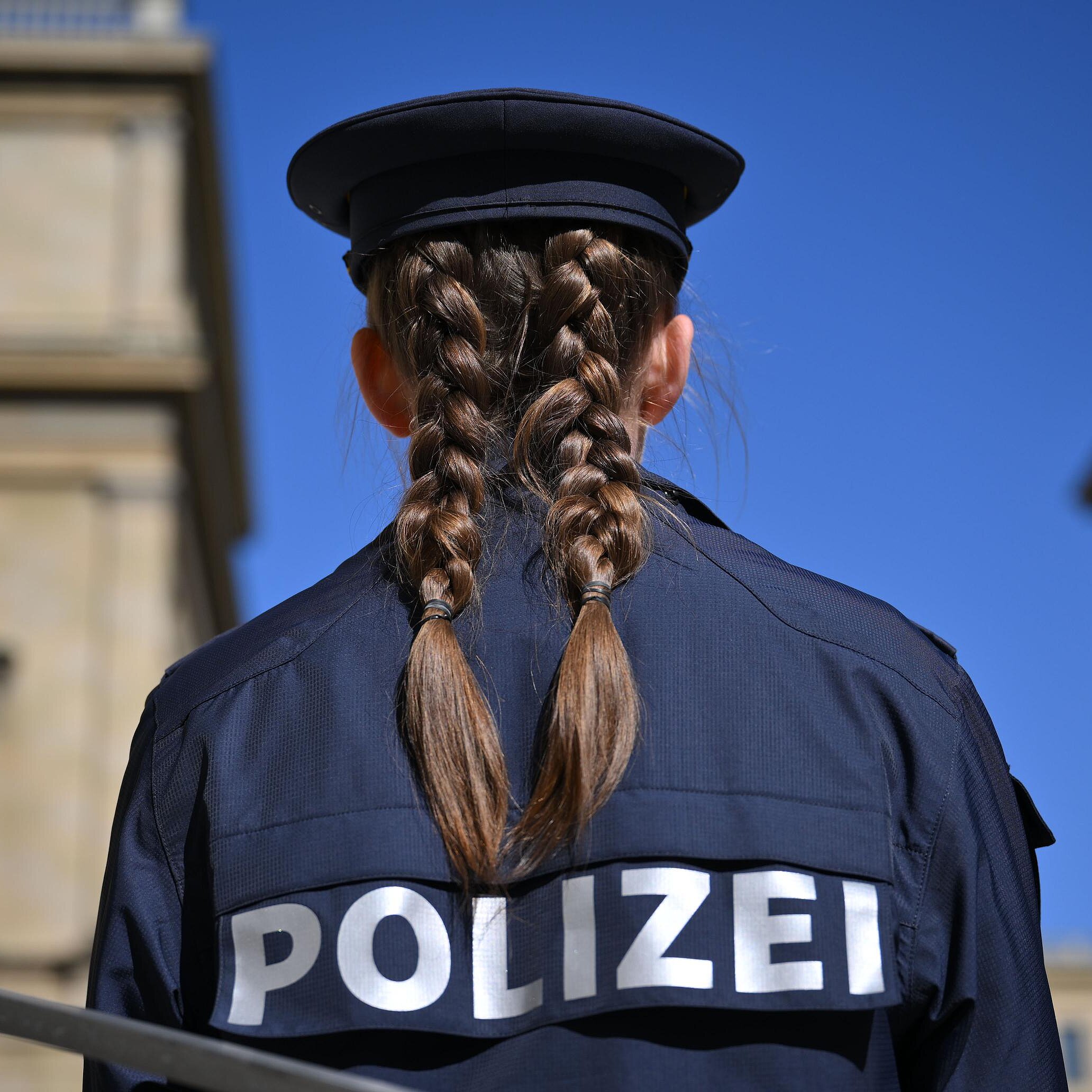 Polizistin von hinten, im  Hintergrund Gebäude in München