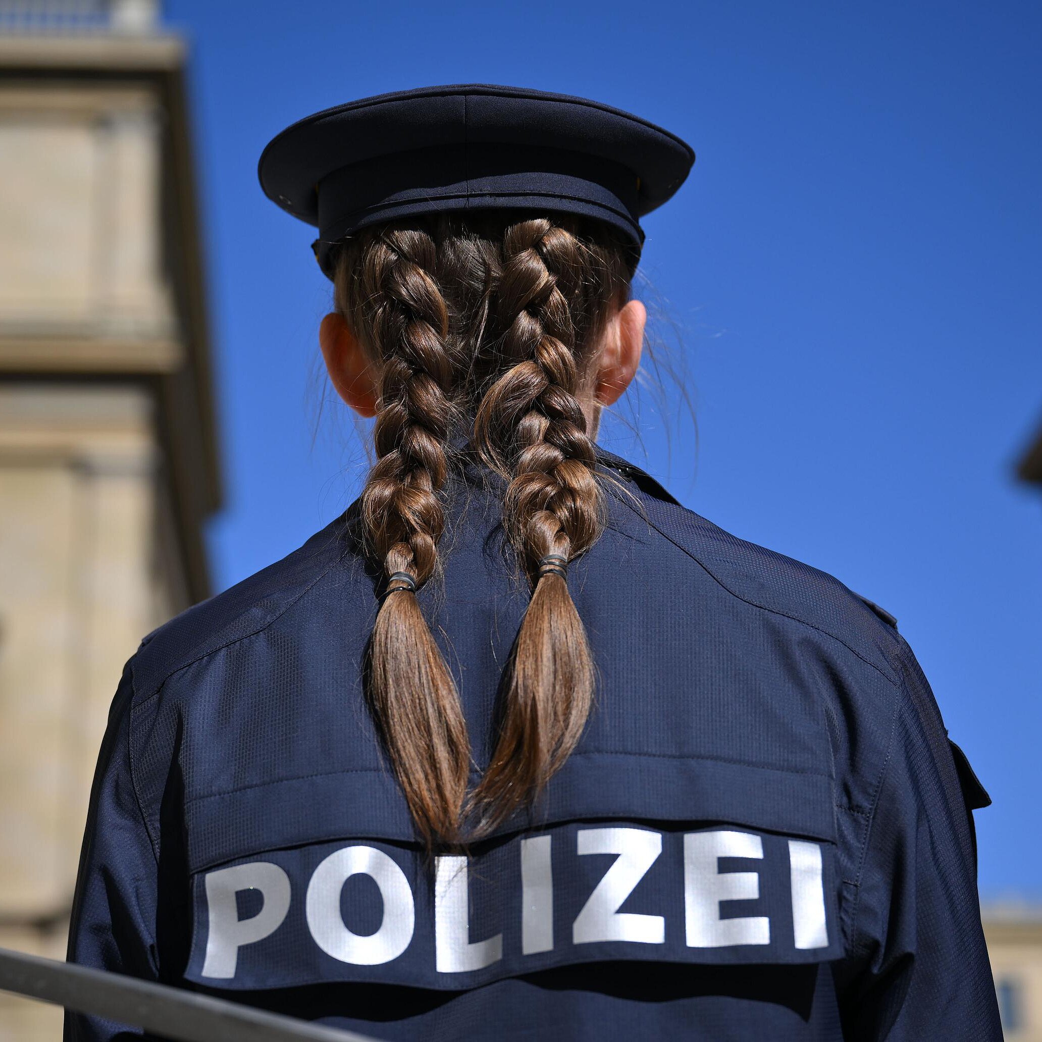 Polizistin von hinten, im  Hintergrund Gebäude in München