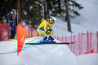 Luisa Klapprott Skifahrerin in gelbem Rennanzug springt über Kuppe beim Skicross, Gesicht unkenntlich.