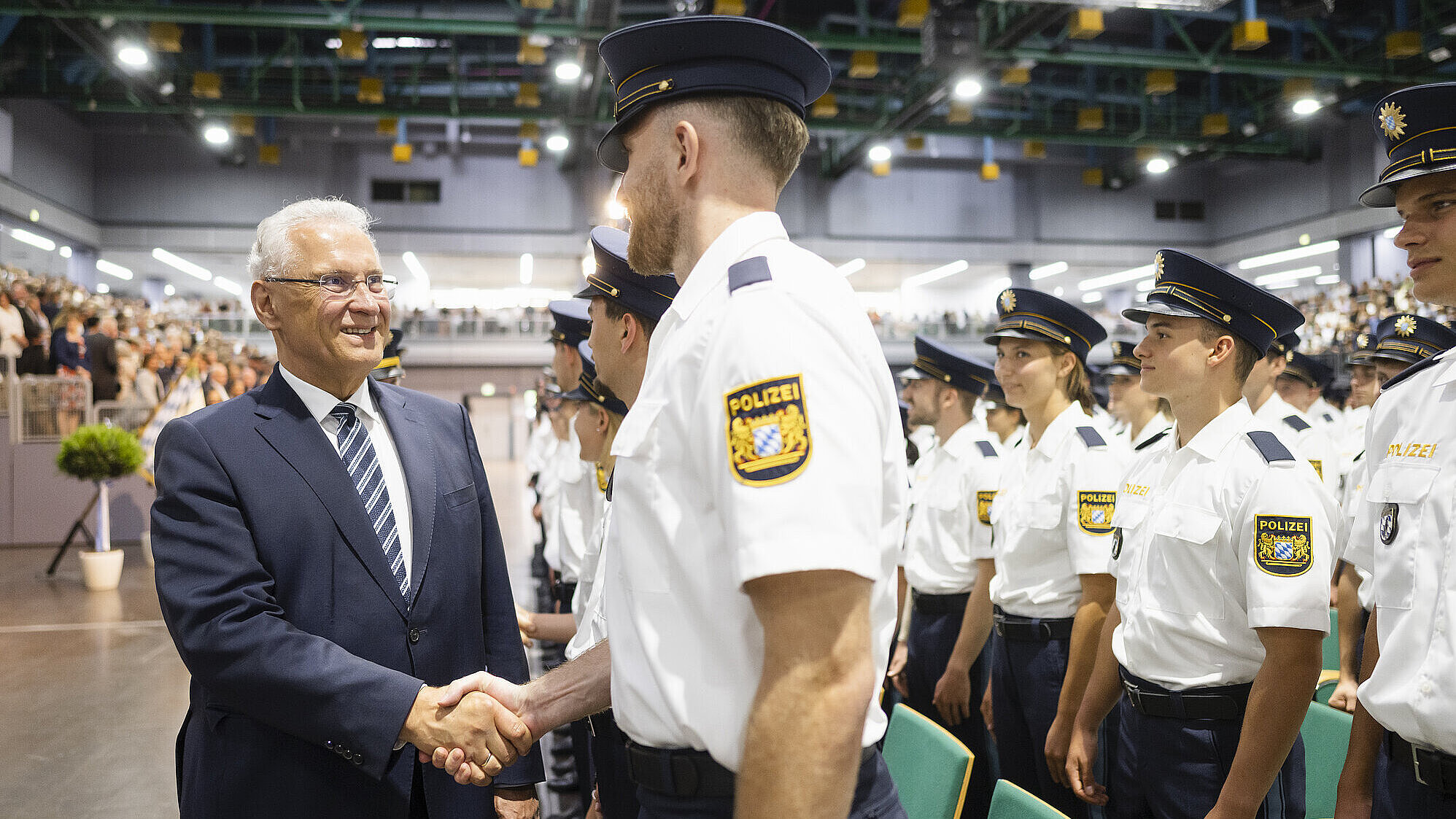 Herrmann schüttelt Polizist die Hand, rechts viele weitere Polizisten