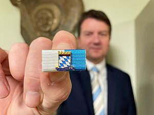 Staatssekretär Sandro Kirchner der die Fluthelfernadel in die Kamera hält