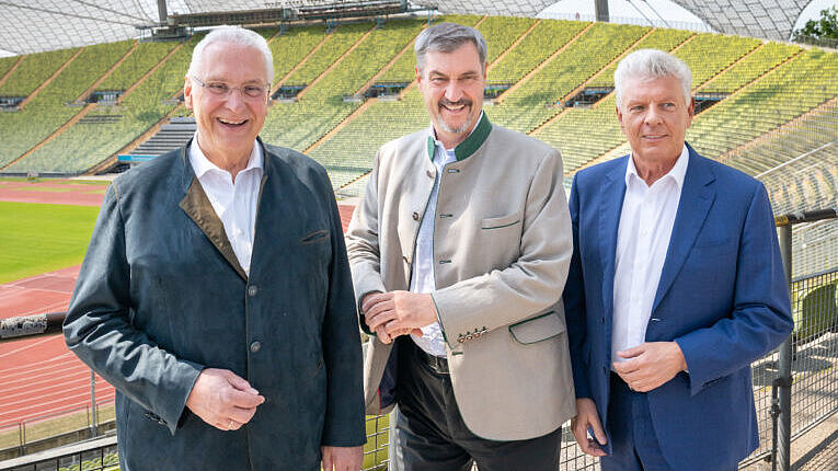 von links Innenminister Joachim Herrmann, Ministerpräsident Dr. Markus Söder, Oberbürgermeister Dieter Reiter im Olympiastadion im Hintergrund die Tartlaufbahn und das Dach des Olympiastadions