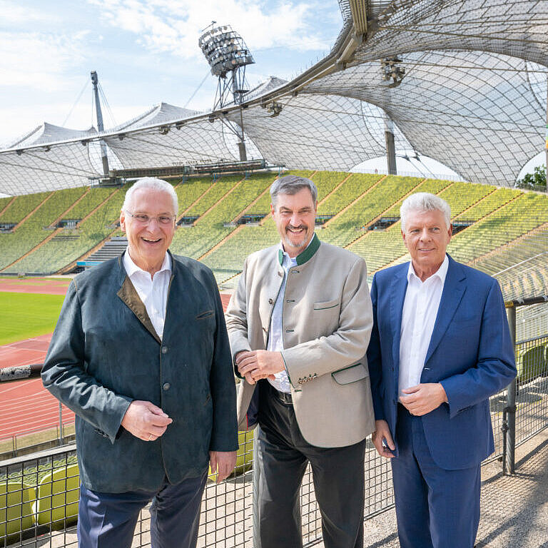 von links Innenminister Joachim Herrmann, Ministerpräsident Dr. Markus Söder, Oberbürgermeister Dieter Reiter im Olympiastadion im Hintergrund die Tartlaufbahn und das Dach des Olympiastadions