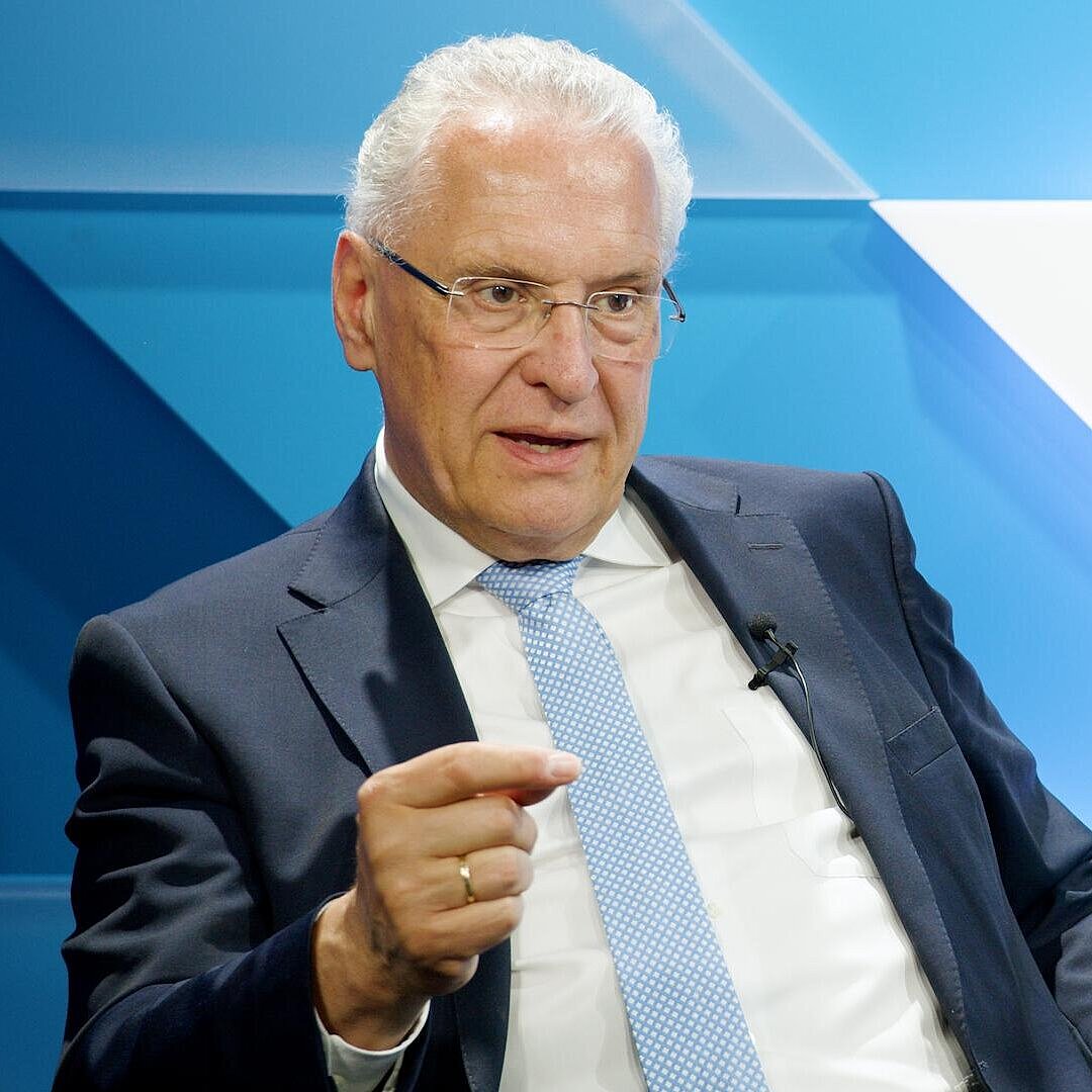 Innenminister Joachim Herrmann sitzend und gestikulierend, nachdenklicher Blick