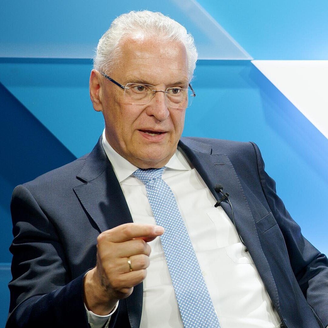 Innenminister Joachim Herrmann sitzend und gestikulierend, nachdenklicher Blick