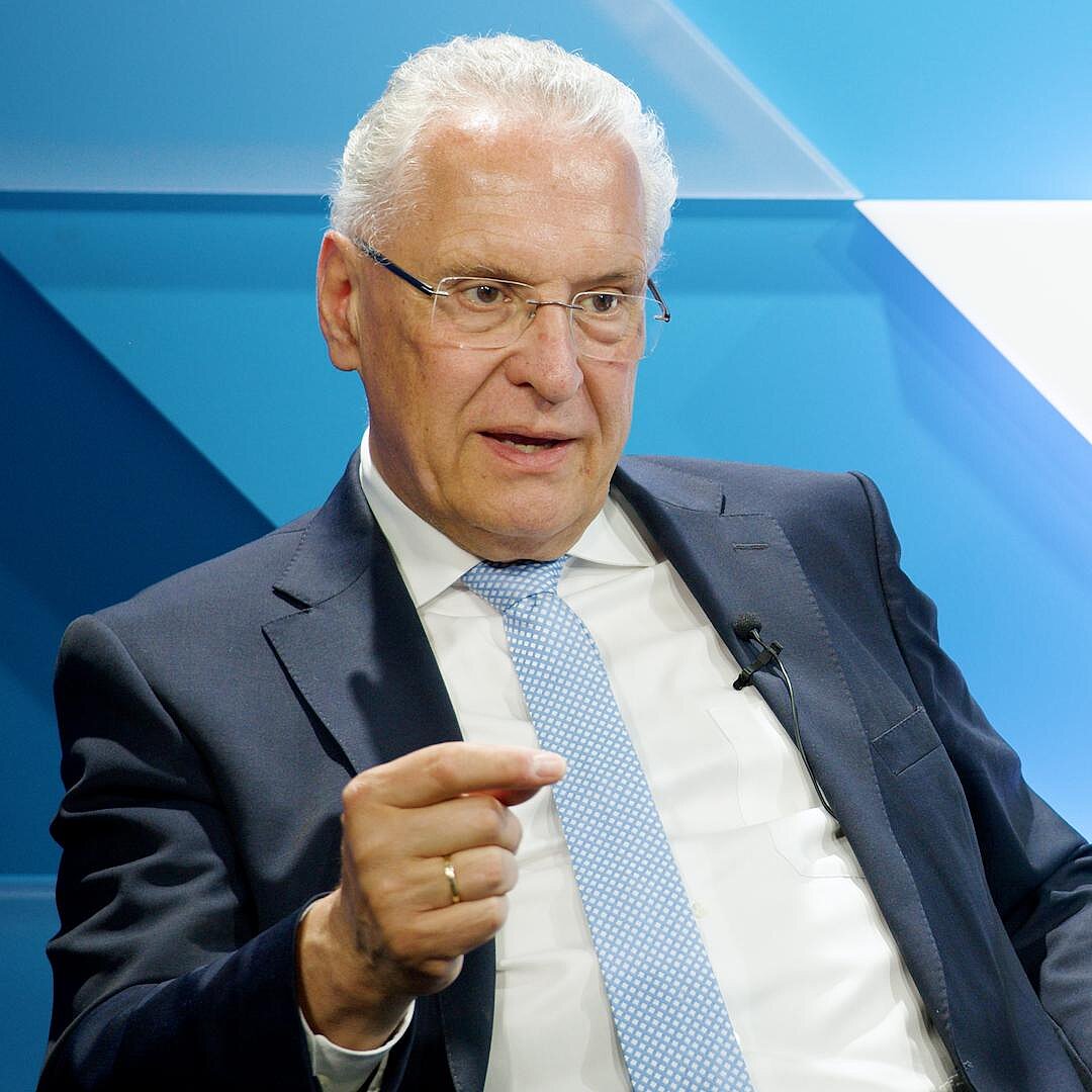 Innenminister Joachim Herrmann sitzend und gestikulierend, nachdenklicher Blick