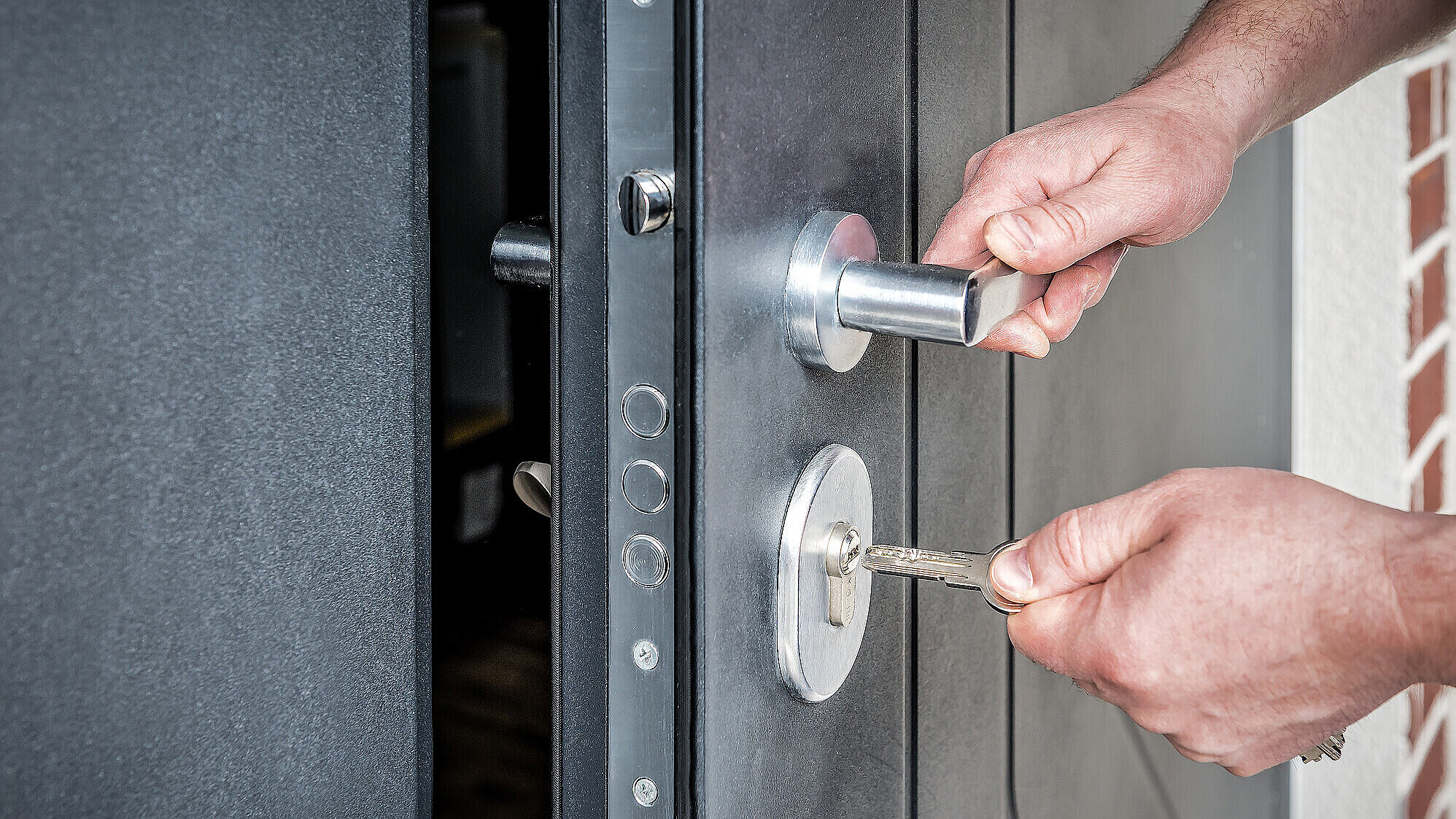 Hand putting house key into front door lock of new house