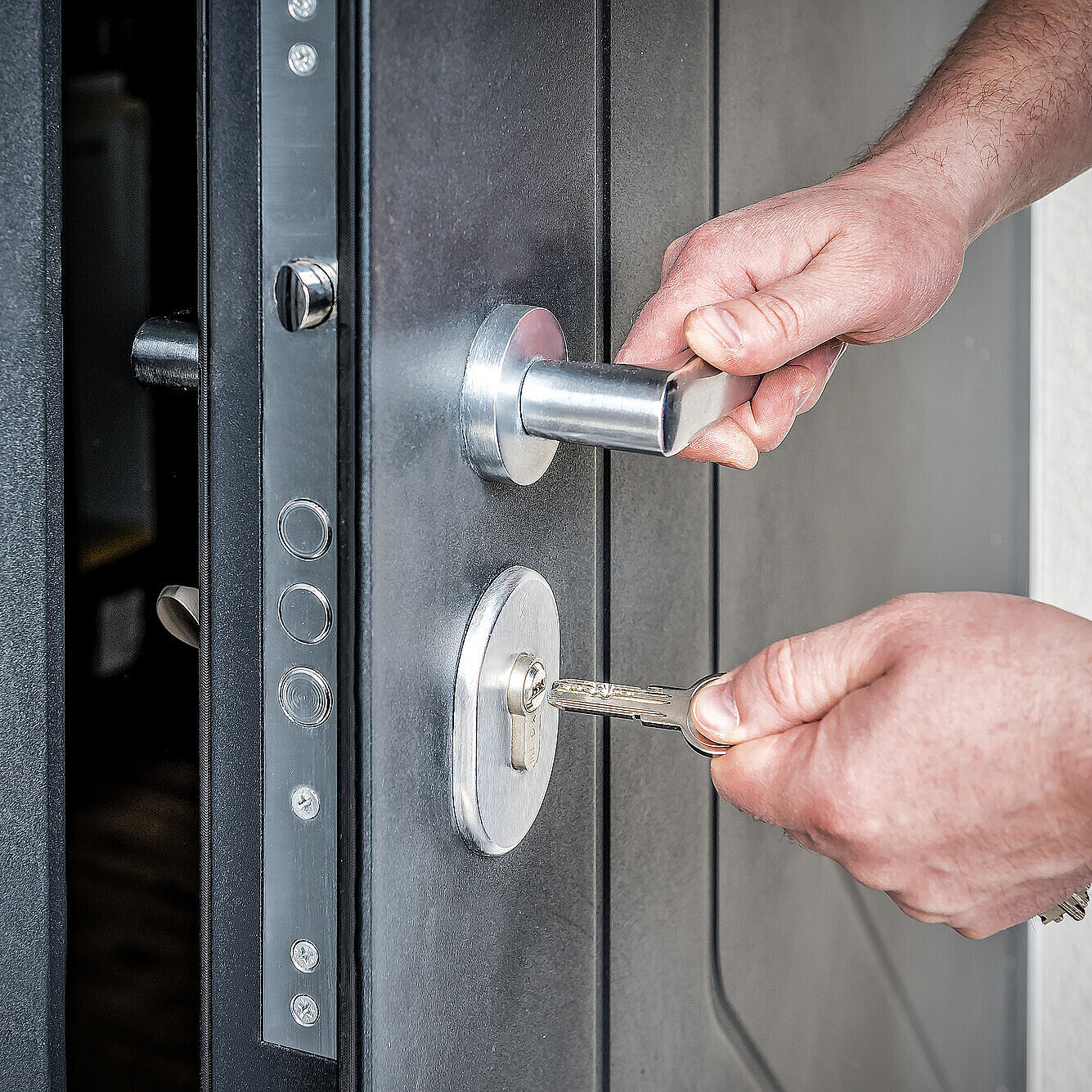 Hand putting house key into front door lock of new house